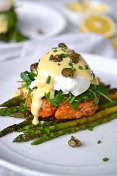 a white plate topped with asparagus covered in mayonnaise and other toppings