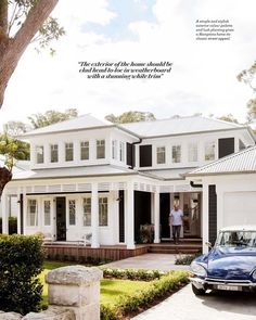 a blue car is parked in front of a white house with black shutters and windows