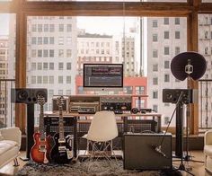 a living room filled with lots of furniture and musical equipment in front of a large window