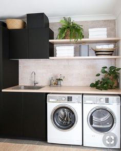 a washer and dryer in a small room with black cabinetry on the wall