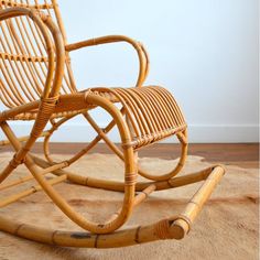 a wicker rocking chair sitting on top of a wooden floor next to a rug