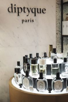 bottles of perfume are arranged on a table in front of a sign that says diptyque paris