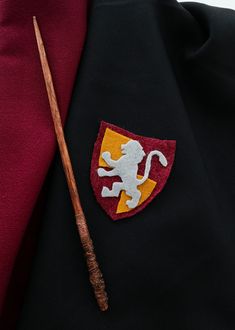 a harry potter costume with a wand and crest on the lapel of his jacket