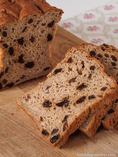 sliced loaf of bread sitting on top of a wooden cutting board with raisins