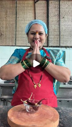 a woman standing in front of a wooden table with food on it and making a hand gesture