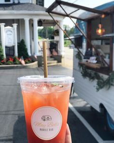 a person holding up a drink in front of a house