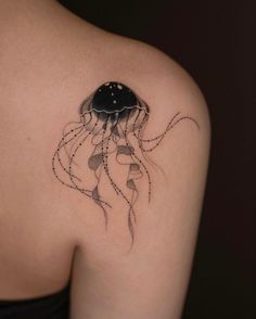 a woman's back shoulder with a black and white jellyfish tattoo on it