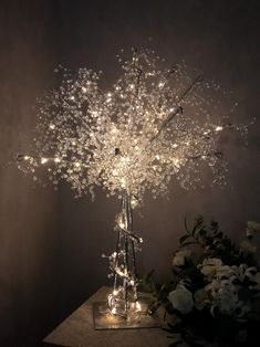 a vase filled with lots of lights sitting on top of a table next to flowers