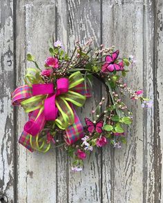 a pink and green wreath on a wooden door