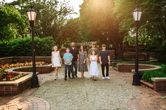 a group of people standing next to each other in front of some trees and bushes