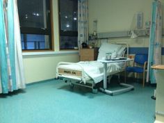 a hospital room with a bed, desk and chair