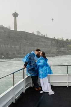 a man and woman kissing on the deck of a boat in front of a waterfall