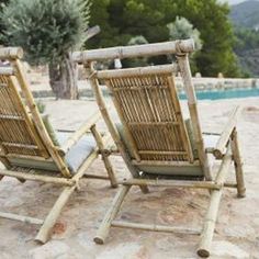 two lawn chairs sitting next to each other on top of a sandy beach near a swimming pool