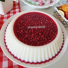 a white plate topped with red jelly next to other plates filled with fruit and desserts