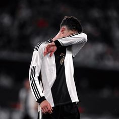 a soccer player is holding his head while standing on the field with his hands behind his back