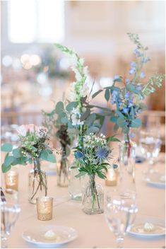 there are many vases with flowers in them on the table at this wedding reception