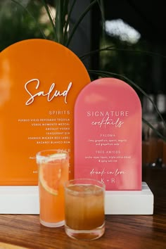 a table topped with two glasses filled with liquid and an orange plate next to it