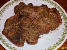 two pieces of meat sitting on top of a white and green plate with sprinkles