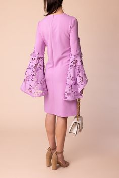 a woman in a pink dress with bell sleeves and lace detailing on the shoulders, back view