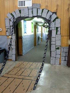 an arch made out of cardboard is in the middle of a room with a door