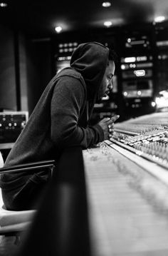 a man sitting at a mixing desk with headphones in his hands and looking down