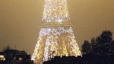 the eiffel tower lit up at night with lights on it's sides