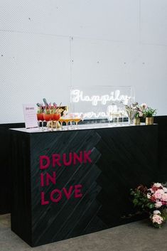 a table with drinks and flowers on it that says drunk in love written on the side