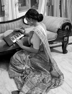 a woman is sitting on the floor with an old fashioned piano in her lap top