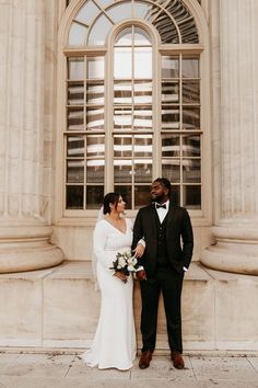 a bride and groom standing in front of an old building