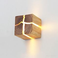 a wooden wall light with a cross cut out of it's wood and glowing from the inside