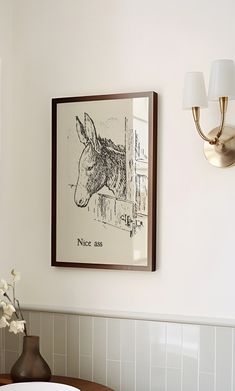 a bathroom with a sink, mirror and framed artwork on the wall next to it