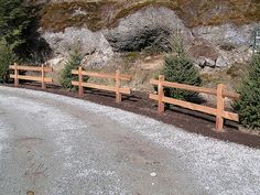 three wooden benches sitting on the side of a road next to some rocks and trees