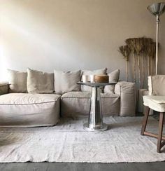 a living room with a white couch and table in the middle, surrounded by pillows