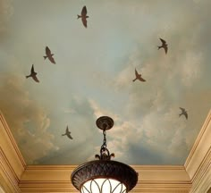 birds are flying in the sky above a chandelier and painted ceiling with clouds