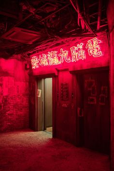 an empty room with red lights and chinese writing on the wall above it is a doorway that leads to another room