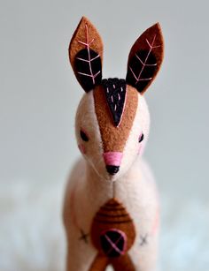 a small stuffed animal with leaves on it's head and ears, sitting on a white surface