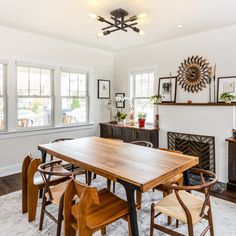 a dining room table and chairs in front of a fireplace with pictures on the wall