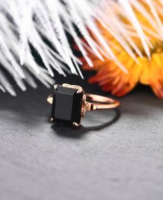 a black diamond ring sitting on top of a table next to some orange and white flowers