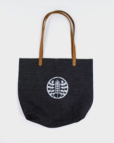 A simple everyday tote to carry your belongings or groceries. Keep it simple or use it as a canvas for patchwork. Made here in our Portland studio, with high-quality selvedge denim and leather. Screenprinted with Kiriko's emblem, representing indigo leaves and dyes. Sewn in Portland, OR Screen printed on one side, blank on the other Leather handle, Brass rivets Inside pocket Size: 17" x 15.5" Product #: CT04 Code: WP50 Everyday Denim Tote Canvas Bag, Denim Blue Cotton Bags For Everyday Use, Denim Tote Canvas Bag For Everyday Use, Everyday Denim Blue Canvas Shoulder Bag, Denim Blue Cotton Shoulder Bag For Everyday Use, Everyday Denim Blue Cotton Shoulder Bag, Denim Blue Canvas Tote Bag, Everyday Use Tote Bag With Leather Patch, Leather Patch Tote Bag For Everyday Use