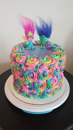 there is a cake decorated with swirly icing and two small figurines on top