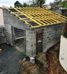 a house under construction with yellow rafters on it's roof and pipes attached to the wall