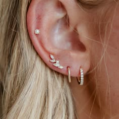 a close up of a woman's ear with three small diamond studs