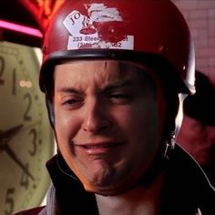 a man wearing a red helmet standing in front of a clock