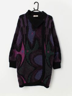 80s vintage thick cardigan coat in purple, pink and green. This black 1980s cardigan features a funky purple, pink, blue and green geometric pattern, has a one button closure on the neck and is made from a heavyweight wool blend. Our recommended size: Medium to large Label says: Medium  Condition: Very good Material: 70% wool, 20% acrylic, 10% nylon Measurements in inches: Pit to pit: 24 Shoulders: 23 Front length: 34.5 Back length: 34.5 Sleeve length: 20.5 Hem: 22 We recommend that you compare Retro Cotton Cardigan With Patchwork, Vintage Purple Cardigan For Winter, Purple Patchwork Cardigan, Multicolor Retro Patchwork Cardigan, One-size Multicolor Patchwork Cardigan, Thick Cardigan, Cardigan Coat, Cardigans For Women, Wool Blend