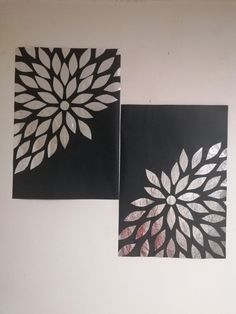 two black and white paintings on a wall with silver foil flowers in the middle, one is cut out to look like leaves