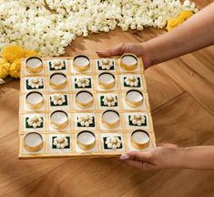 a person is holding a board game with cups and saucers in front of them