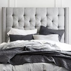 an upholstered bed with pillows and blankets is shown in black and white colors