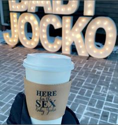 a cup of coffee sitting on top of a table next to a light up sign