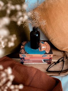 a stack of books sitting on top of a bed next to a pillow