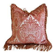 a red and white pillow with tassels on it